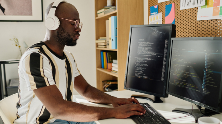 homem em frente a telas de computador representando o dia do programador